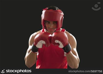 Portrait of male boxer wearing head protector and gloves isolated over black background