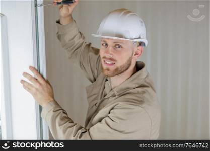 portrait of male builder using screwdriver on door hinge