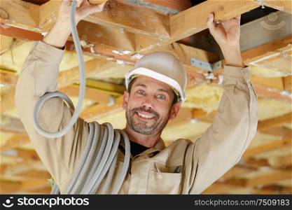 portrait of male builder with reel of cable on shoulder