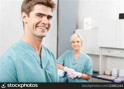Portrait of male dentist with female assistant standing at dental clinic. Male dentist with female assistant standing at dental clinic