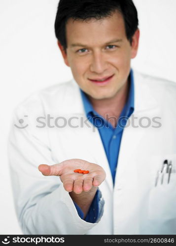 Portrait of male doctor holding pill on his palm