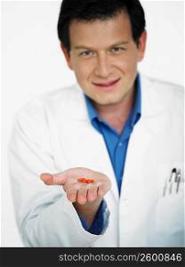 Portrait of male doctor holding pill on his palm