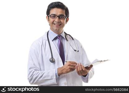 Portrait of male doctor writing on clipboard over white background