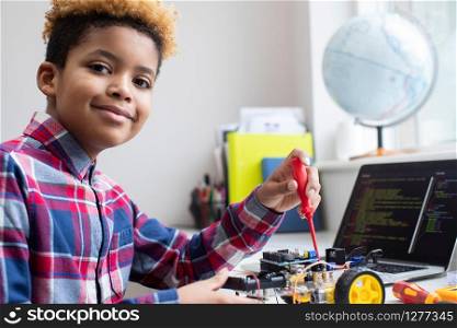 Portrait Of Male Elementary School Pupil Building Robot Car In Science Lesson