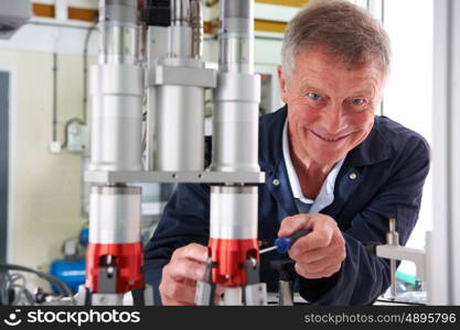 Portrait Of Male Engineer Working On Machine In Factory