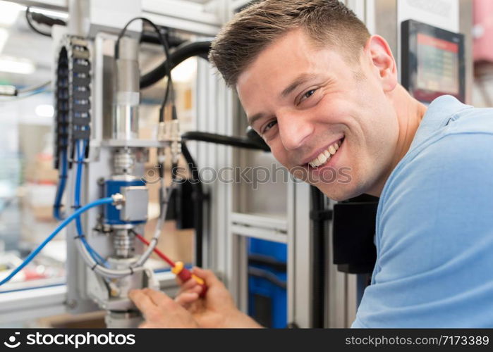 Portrait Of Male Engineer Working On Machine In Factory