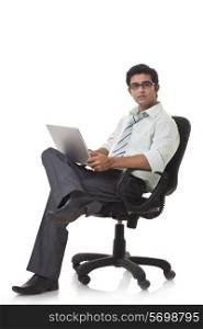 Portrait of male executive on office chair using laptop