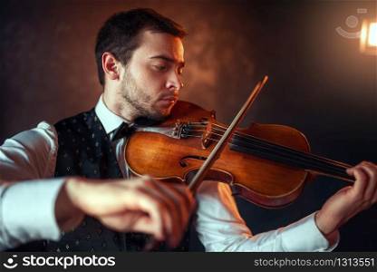 Portrait of male fiddler playing classical music on violin. Violinist man with musical instrument