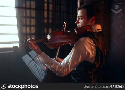 Portrait of male fiddler playing classical music on violin. Violinist man with musical instrument. Male fiddler playing classical music on violin