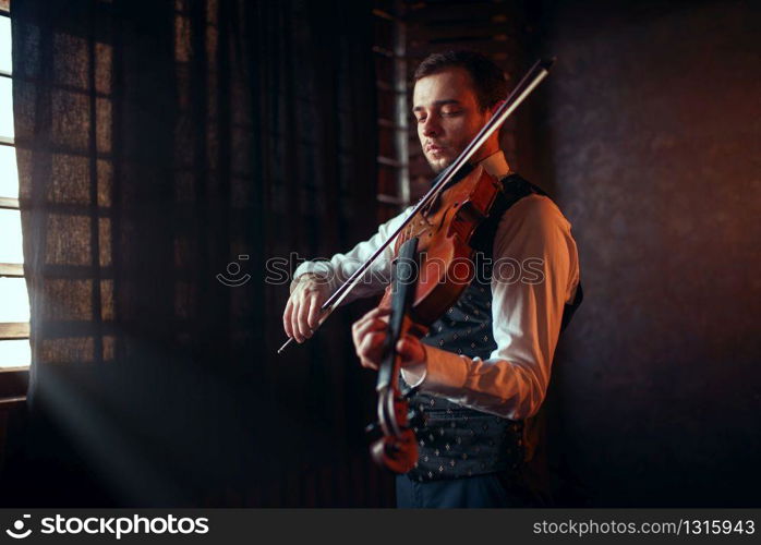 Portrait of male fiddler playing classical music on violin. Violinist man with musical instrument. Male fiddler playing classical music on violin