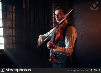 Portrait of male fiddler playing classical music on violin. Violinist man with musical instrument. Male fiddler playing classical music on violin