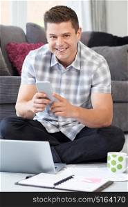 Portrait Of Male Freelance Worker Using Mobile Phone At Home