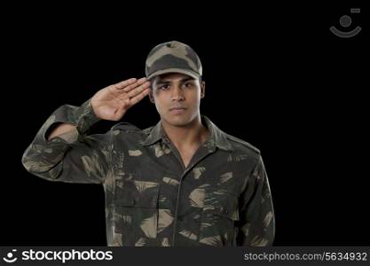 Portrait of male Indian soldier saluting over black background