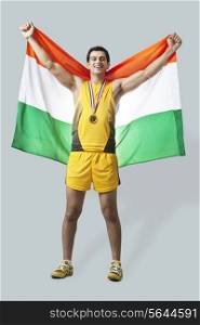 Portrait of male medalist celebrating victory with Indian flag against gray background