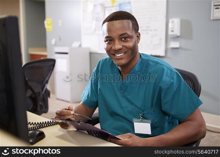 Portrait Of Male Nurse Working At Nurses Station