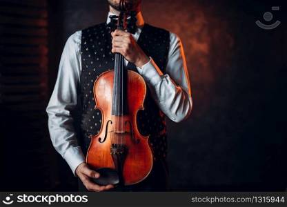 Portrait of male person holding wooden violin. Fiddler with musical instrument