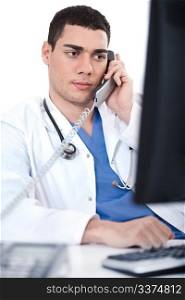Portrait of male physician holding receiver and looking the computer at white background