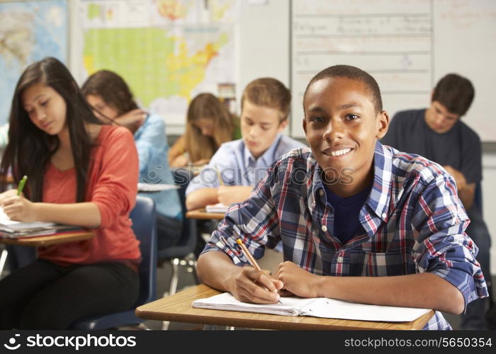 Portrait Of Male Pupil Studying At Desk In Classroom