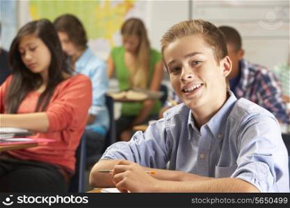 Portrait Of Male Pupil Studying At Desk In Classroom