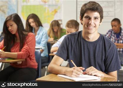 Portrait Of Male Pupil Studying At Desk In Classroom