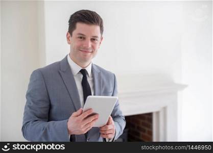 Portrait Of Male Realtor With Digital Tablet Looking Around And Valuing New Home