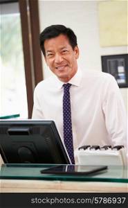 Portrait Of Male Receptionist At Hotel Front Desk