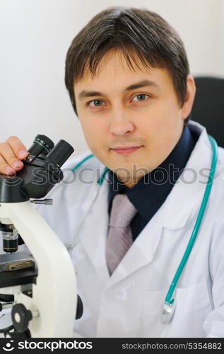 Portrait of male researcher working with microscope