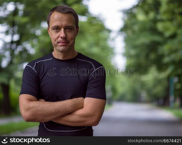 portrait of male runner. portrait of fit muscular male runner training for marathon running on beautiful road in nature.