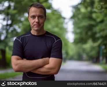 portrait of male runner. portrait of fit muscular male runner training for marathon running on beautiful road in nature.