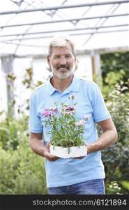 Portrait Of Male Sales Assistant At Garden Center Holding Plants