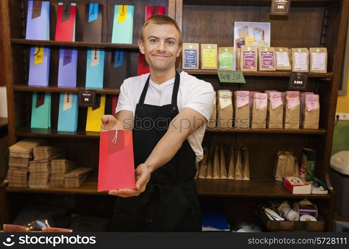 Portrait of male salesperson showing product in coffee store