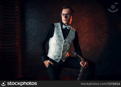 Portrait of male saxophonist with saxophone, jazz man with sax. Classical brass band instrument. Male saxophonist with saxophone, jazz man with sax