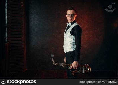 Portrait of male saxophonist with saxophone, jazz man with sax. Classical brass band instrument. Male saxophonist with saxophone, jazz man with sax