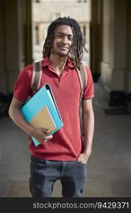 Portrait Of Male Student Carrying Files Outside University Building In Oxford UK