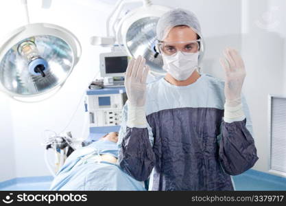 Portrait of male surgeon in operation theatre with patient in background