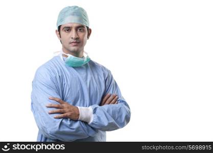 Portrait of male surgeon with hands folded over white background