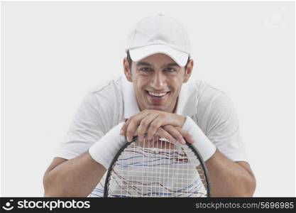 Portrait of male tennis player with racket isolated over gray background
