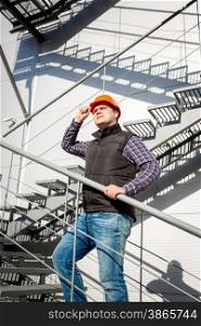 Portrait of male worker in hardhat standing on steel staircase