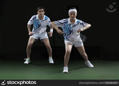 Portrait of man and woman playing badminton doubles at court