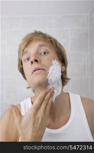 Portrait of man applying shaving cream in bathroom