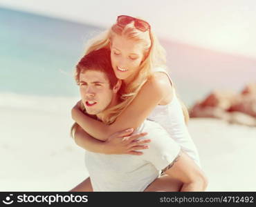 Portrait of man carrying girlfriend on his back. Portrait of man carrying girlfriend on his back on the beach