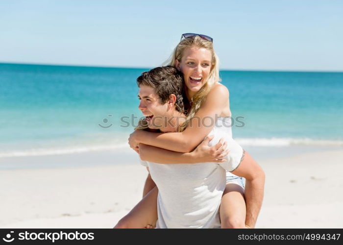 Portrait of man carrying girlfriend on his back. Portrait of man carrying girlfriend on his back on the beach