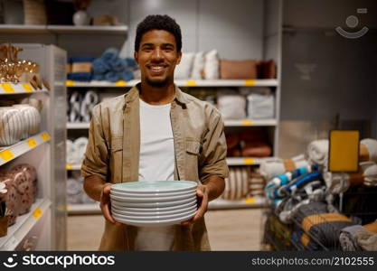 Portrait of man carrying new purchased in shop plate stack. Guy shopping for new home apartment. Portrait of man carrying purchased plate stack