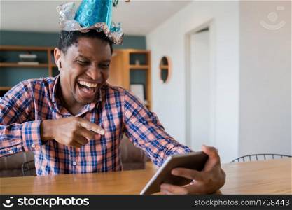 Portrait of man celebrating birthday on a video call with digital tablet at home.New normal lifestyle concept.