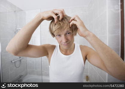 Portrait of man checking for white hair in bathroom