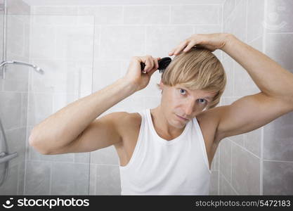 Portrait of man combing hair in bathroom