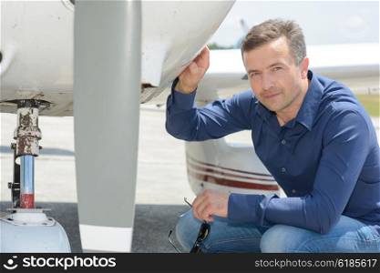 Portrait of man crouching by aircraft