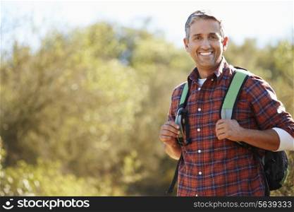 Portrait Of Man Hiking In Countryside Wearing Backpack