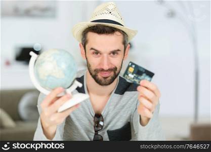 portrait of man holding globe and credit card