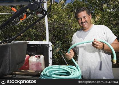 Portrait of man holding hose in garden